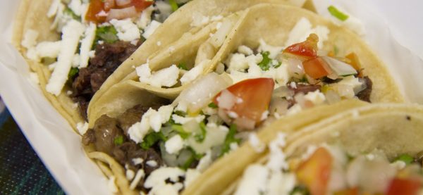 Close-up photo of tacos with meat, cheese, and vegetables