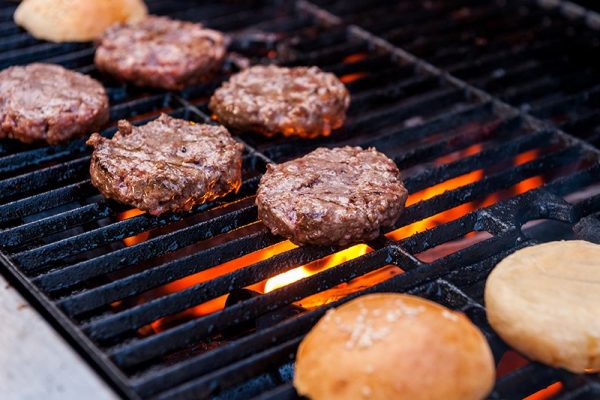 A grill with burgers and buns on it